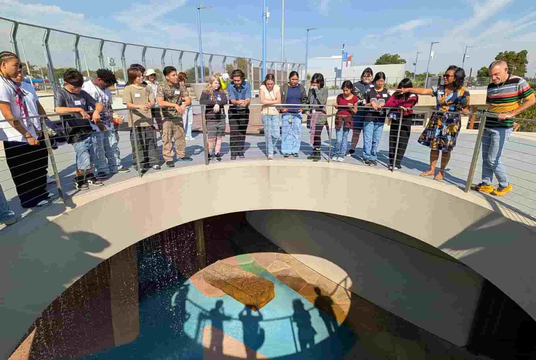 un grupo de jovenes con adultos ven su reflejo desde un puente levadizo